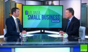 Two men sitting in front of a tv, discussing the advantages of adopting a franchise on the Atlanta Small Business Show.