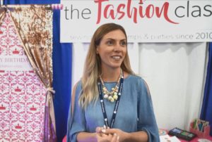 A CEO standing in front of a booth at a fashion show.